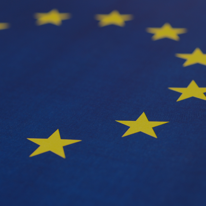 Close-up of the EU flag with yellow stars on a blue background.